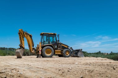 Kazıcı arazi inşaatı için arazi üzerinde çalışıyor.