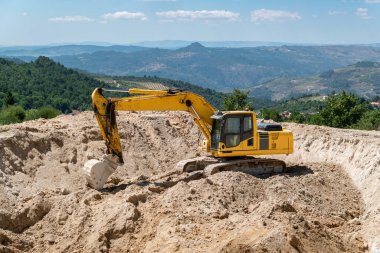 Güneşli bir günde tarımsal sulama için su depolamak için bir baraj inşa eden kazıcı