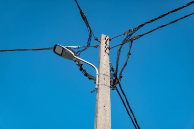 Ortasında lamba ve kablolar olan sokak lambası direği.