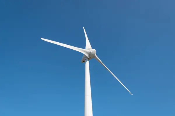 Güneşli bir günde büyük bıçaklarıyla elektrik üreten rüzgar türbini.