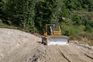 Ön bıçaklı buldozer yeni bir yol inşaatı için zemini düzleştiriyor.
