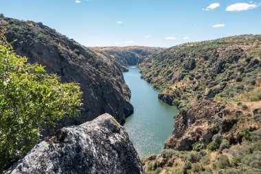 Etrafı kayalık dağlarla çevrili, Miranda do Douro nehri mavi gökyüzünün altında.