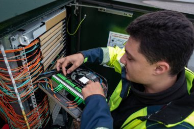 Fiber optik teknisyen arızadan etkilenen müşterilere ağ erişimini geri getirmek için bir dolap üzerinde onarım yapıyor