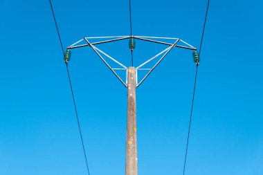 Açık mavi gökyüzüne karşı yüksek voltajlı elektrik direği