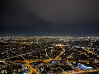 Paris 'in gece manzarası. Işıklar, karanlık gökyüzünün altında mimariyi ve sokakları canlı renklerle aydınlatıyor.