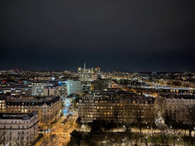 Geceleri Paris 'in panoramik manzarası. Şehir, karanlık gökyüzüne karşı mimari ve işlek caddeleri aydınlatan yapay ışıklarla aydınlanıyor.