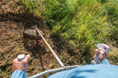 Fırçalı tarım işçisi kırsal bir çiftlikte yabani otları kesiyor.