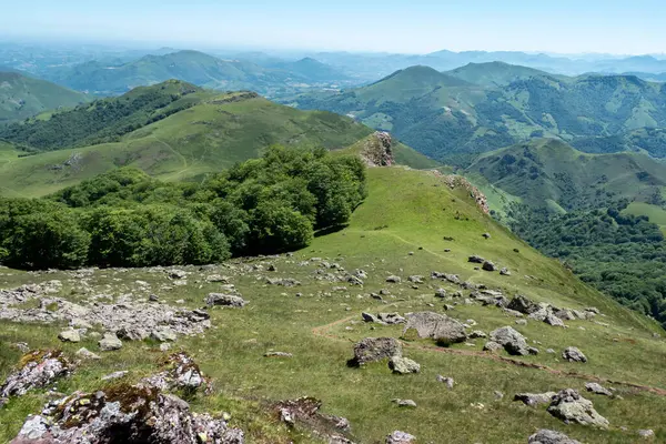 Fransa 'daki Autza Dağı' nın tepesinden panoramik manzara. Önde gelen kayalar ve arka planda geniş yeşil alanlar ve ormanlar.