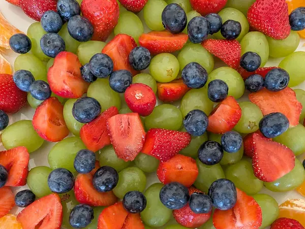 Çeşitli taze meyveli meyve salatası; üzümler, çilekler ve yabanmersinleri, sağlıklı bir aperatif veya tatlı için hazır.