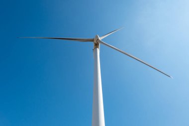 Beyaz rüzgar türbini ya da yenilenebilir enerji jeneratörü açık mavi gökyüzünün altında güçlü güneş ışığı altında
