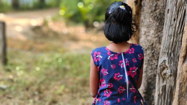 Üzgün küçük kız geriye dönüp bir şeyler düşünüyor. Bulanık yeşil arkaplan, kopyalama alanı 