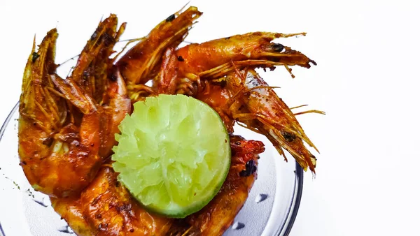 Beyaz arka plan fotokopi alanı üzerinde limonla servis edilen kızarmış karidesler, beyaz arka planda baharatlı soslu yüksek ateşte kızartılmış EBI karideslerinden görüş..
