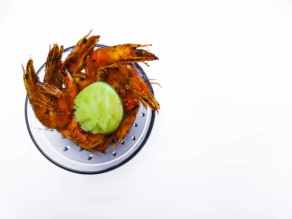Beyaz arka plan fotokopi alanı üzerinde limonla servis edilen kızarmış karidesler, beyaz arka planda baharatlı soslu yüksek ateşte kızartılmış EBI karideslerinden görüş..