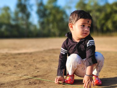 Parkta iple oynayan ve gülümseyen sevimli bir erkek bebek. Çocuk halka açık bir parkta sürünüyor ve mutlu bir yüzle yukarı bakıyor. Alttan bak. Boşluğu Kopyala Seçici odak 