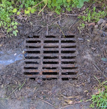 Yağmurdan sonra kaldırımda metal kanalları temizlemek..