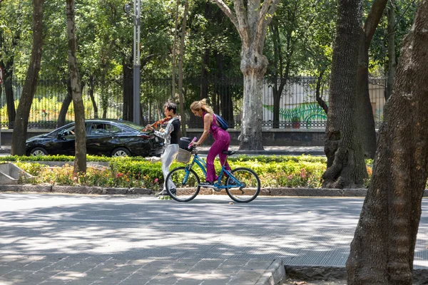 Mexico City, Meksika, 07 Mayıs 2023: Bisikletli kadın ve Chapultepec Park 'ın önünde paten kayan erkekler. Yüksek kalite fotoğraf