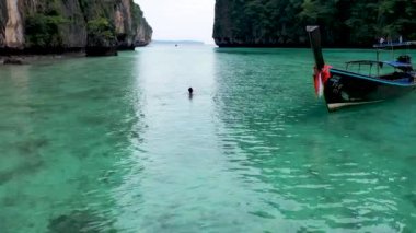 Drone Shot of an Asian man enjoying the sea close with traditional boat in Pi Leh Bay, Thailand.