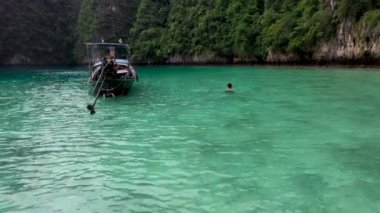 Drone Shot of an Asian man enjoying the sea close with traditional boat in Pi Leh Bay, Thailand.