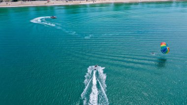 Bir turistin teknesiyle deniz paraşütü yaparken yukarıdan görünüşü.