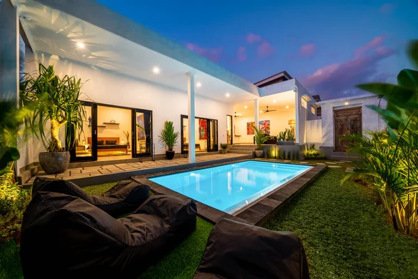 Tropischer Villenblick Mit Garten Pool Und Offenem Wohnzimmer Bei Sonnenuntergang lizenzfreie Stockbilder
