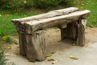 Parkta çimenli odun parçalarından yapılmış bir bank görün