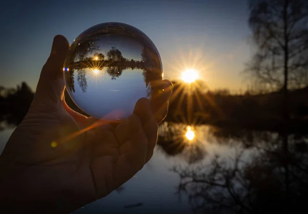 hand holding a globe with a planet in the sky