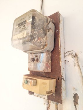Close up of an old model electrical panel in Indonesia attached to a white wall. Side angle view.