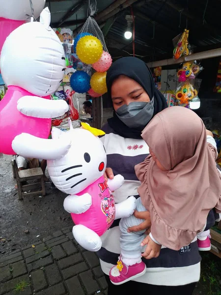 stock image A beautiful hijab-wearing Asian mother wearing a mask is buying cute stuffed toys for her hijab-wearing daughter