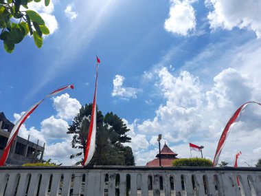 Endonezya bayrakları çitlere bağlı çatıların, ağaçların ve açık mavi gökyüzünün arka planına karşı. Endonezya 'nın bağımsızlık günü, 17 Ağustos. Kırmızı ve beyaz bayrağı kabul et