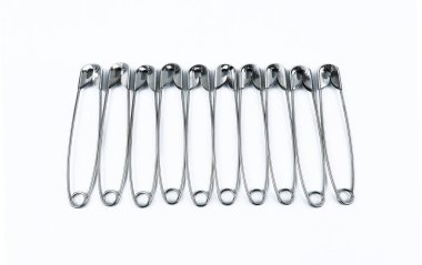 Güvenlik iğneleri yan yana dizilmiş beyaz arka planda izole edilmiş.