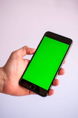 Çeşitli içerikler eklemek için elinde boş yeşil ekranlı bir cep telefonu var.