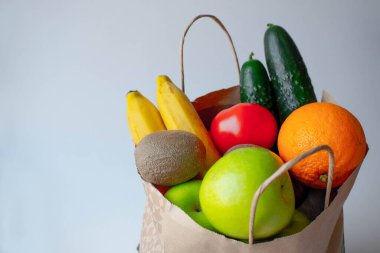 Sağlıklı gıda geçmişi. Kağıt torba içinde sağlıklı vejetaryen yiyecekler beyaz üzerine meyve ve sebzeler, fotokopi alanı, afiş. Süpermarket alışverişi ve temiz vegan gıda konsepti.