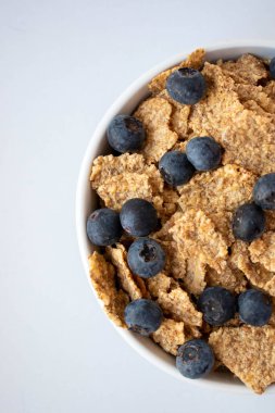 Lezzetli taze kahvaltı, tahıl gevreği ve meyve kâsede servis edilir. Beyaz arka plan. Yakın plan. Üst görünüm.