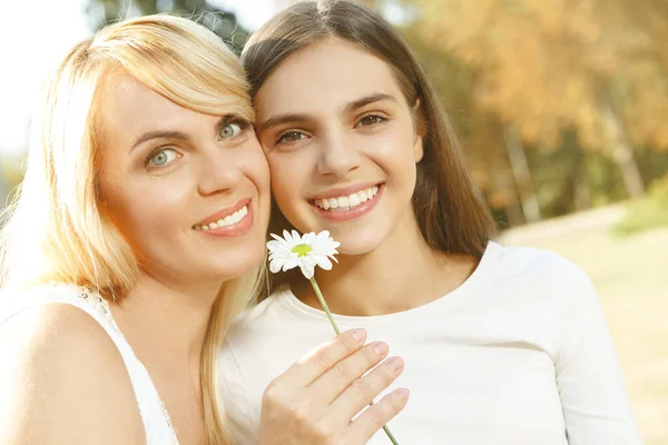 家庭时间 在一个美丽的夏日里 妈妈和女儿抱着一朵花对着摄像机微笑 — 图库照片