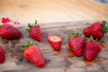 Dışarıdaki ahşap masada ıslak tahtada duran olgun çileklerin olduğu güzel manzaranın önü. Yaz kavramı.
