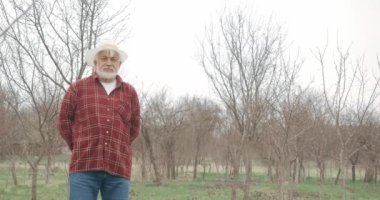 Panama şapkalı yaşlı adamın kameraya baktığı ön manzara. Bahçede gri saçlı ve sakallı bir bahçıvan, kürekle kazıyor. Tarım kavramı.