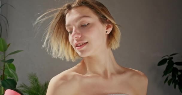 年轻的金发女人穿着毛巾 在浴室吹干头发 动作缓慢 早上使用吹风机的快乐的高加索年轻女性的肖像 美容美发的概念 生活方式 — 图库视频影像