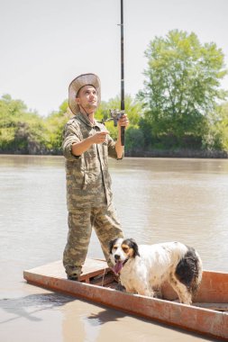 İnce, odaklanmış balıkçı gölde eski püskü bir teknede yüzerken kancaya bakıyor, yakalıyor. Hafta sonları dinlenirken benekli şirin bir köpekle balığa çıkan yorgun bir erkeğin ön görüntüsü. Balık tutma kavramı.