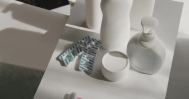 Kozmetik ürünler ve banyo malzemeleri banyodaki beyaz masada. Banyodaki masanın üzerindeki plastik sıvı sabun şişesinin üst görüntüsü, yavaş hareket halinde. Hijyen, spa, sağlık kavramı..
