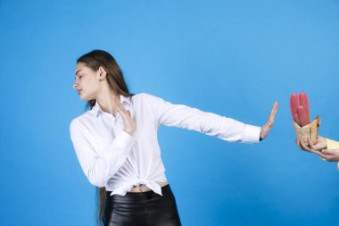 Tatminsiz kız arkasını dönüyor, kaktüs hediyesini reddederek kolunu uzatıyor. Canı sıkkın bir bayanın, isimsiz bir el için, mavi üzerine izole edilmiş kaktüslere dur işareti yapması ön planda. El kol hareketi kavramı.