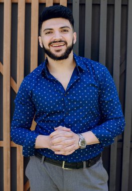 Yakışıklı Asyalı erkek, gülümsüyor ve kameraya bakıyor. Genç işadamı el ele tutuşuyor, resmi tişört ve pantolon giyiyor. Gençlik kavramı.