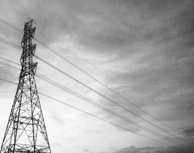 Yüksek voltajlı elektrik hatlarının minimalist siyah beyaz fotoğrafı gökyüzü arka planıyla kesişiyor ve eşsiz ve güzel bir görüntü oluşturuyor..