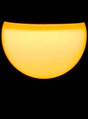 Saf siyah arkaplana karşı parlayan sarı bir ampul telinin soyut yakın çekimi, enerjiyi, fikirleri ve yeniliği sembolize eder.