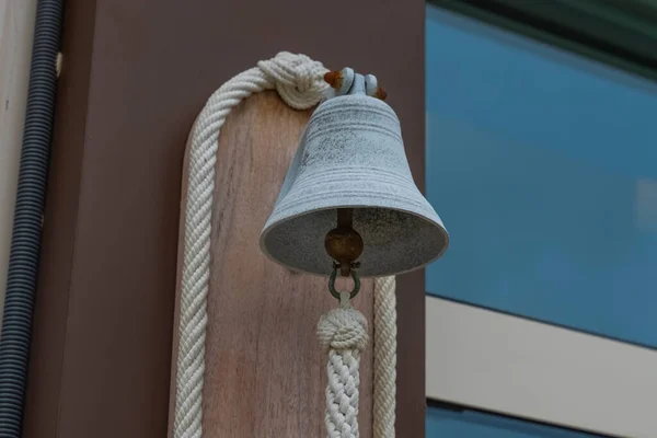 A small metal bell hangs at the entrance to the building. Souvenir bell signifying hospitality. A small bell.
