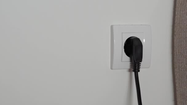 一个男人的手的特写把一根黑电线从一个白色的电源插座拉了出来 — 图库视频影像