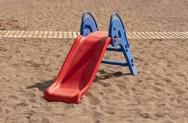一个蓝色红色塑料滑翔机站在度假胜地的海滩上玩耍 海滩上的儿童玩具 — 图库照片