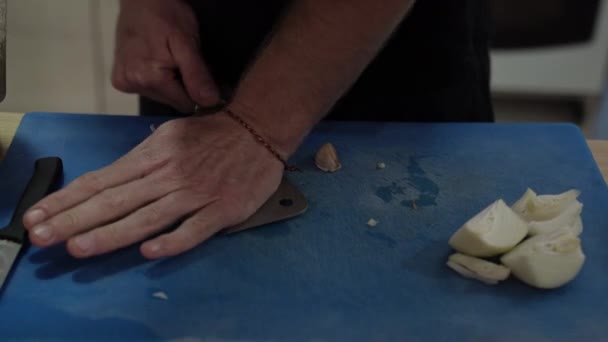ブルー ボーアにニンニクを刻んだ男の手の終わりだ シェフの手を細かく切断板の上に鋭いナイフでニンニクを切る — ストック動画