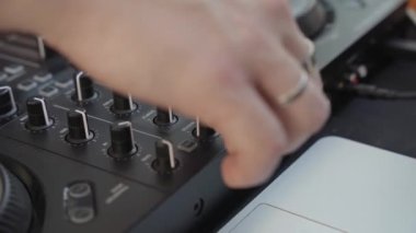 Büyük bir kadın eli, sokaktaki bir konser sırasında siyah bir elektronik DJ panelinde Volume Knob 'u çeviriyor.