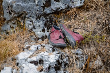 Sokağa atılan yırtık deri ayakkabıların yakın çekimi. İnsan çöpü gezegendeki doğayı kirletiyor..