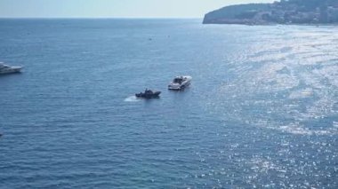 Birçok eski balıkçı teknesi kıyıya yakın demirli demirlerle denizde yüzüyor. Tatil köyünün arka planında eski su taşımacılığı.